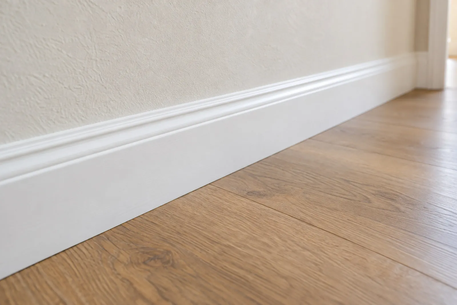 A white baseboard wiped clean along a wood floor.